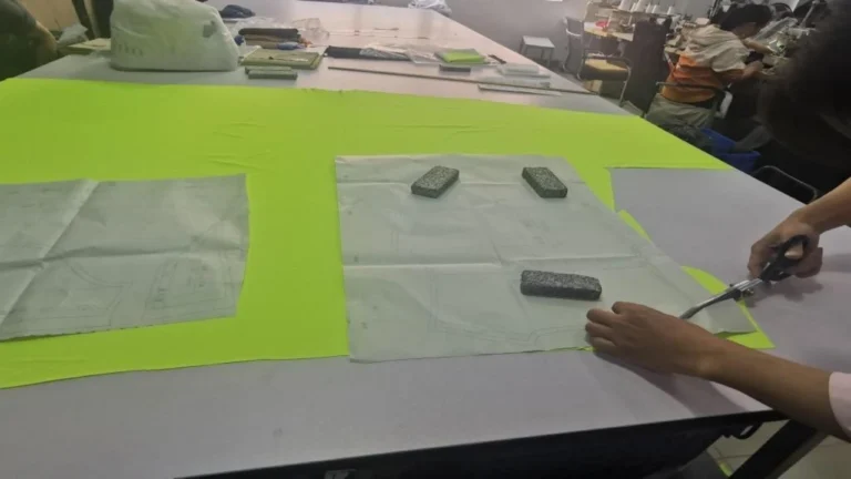 sports shorts manufacturer fabric cutting with patterns and scissors in factory