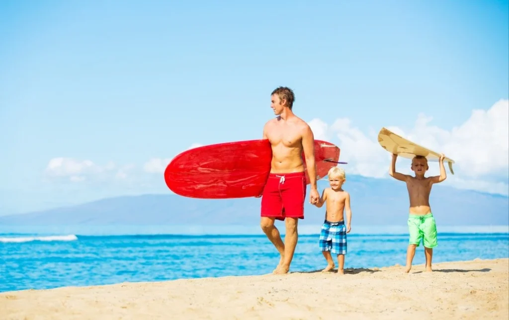 board shorts manufacturer family wearing board shorts at beach with surfboards
